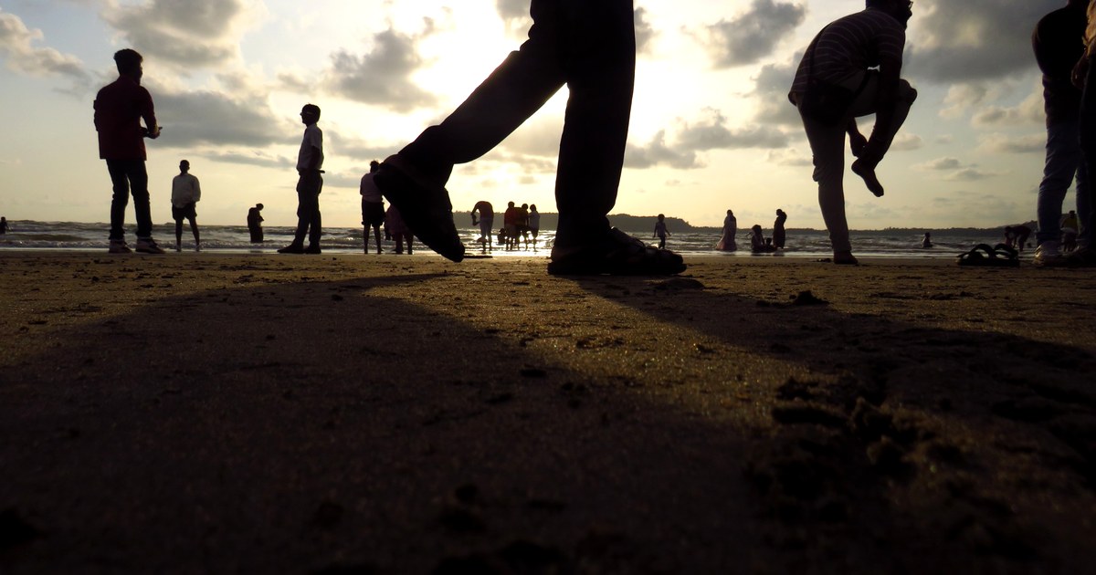 Silhouettes walking across a beach at sunset.